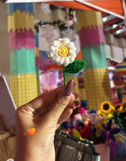 Hand holding a small flower-shaped object with colorful background